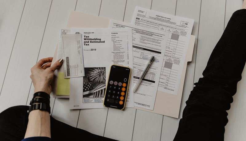 Tax paperwork, a calculator and a phone spread across a desk while working out rates
