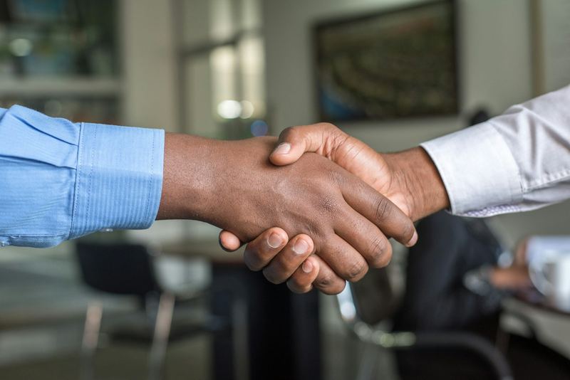 Two people shaking hands to close a business agreement