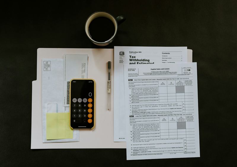 Paperwork, a calculator and a phone on a dark desk while preparing an invoice