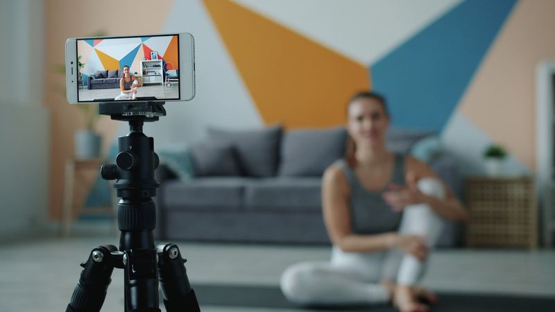 A creator recording a video of herself on a smartphone mounted to a tripod